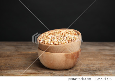 Green buckwheat on wooden table against dark background 105391320
