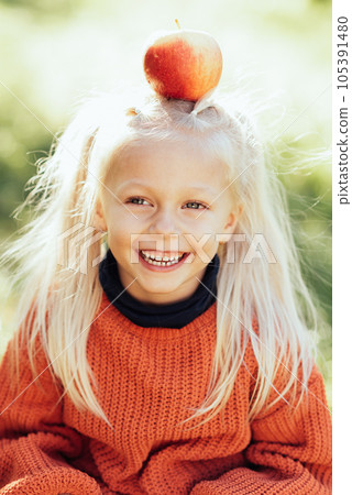 Child picking apples on farm in autumn. Little girl playing in tree orchard. Healthy nutrition. Cute little girl eating red delicious fruit. Harvest Concept. Apple picking. 105391480