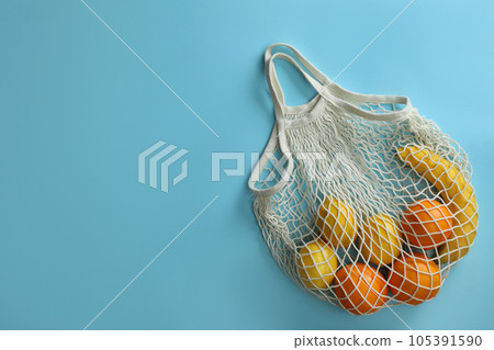 Net bag with fruits on light blue background, top view. Space for text Net bag with fruits on light blue background, top view. Space for text 105391590