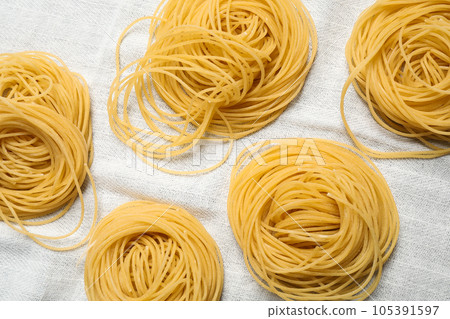 Capellini pasta on white tablecloth, flat lay 105391597