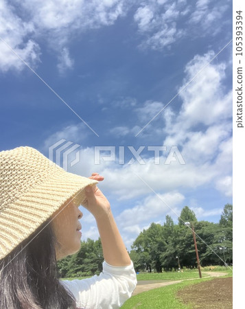 A woman wearing a hat looking up at the sky A woman wearing a hat looking up at the sky 105393394