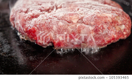 Closeup of steam flowing from cooking burger patty on electric grill. Cooking at home, kitchen appliance, healthy nutrition, hamburger ingredients. 105393465