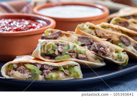 Fajita quesadilla with pieces of beef steak, green bell pepper, onion and cheese, horizontal closeup 105393641