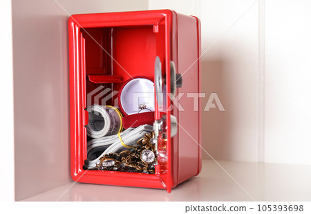 Open red steel safe with money and jewelry on shelf. Space for text Open red steel safe with money and jewelry on shelf. Space for text 105393698