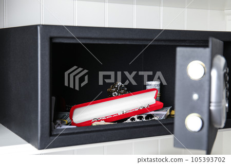 Open black steel safe with money and jewelry on shelf Open black steel safe with money and jewelry on shelf 105393702