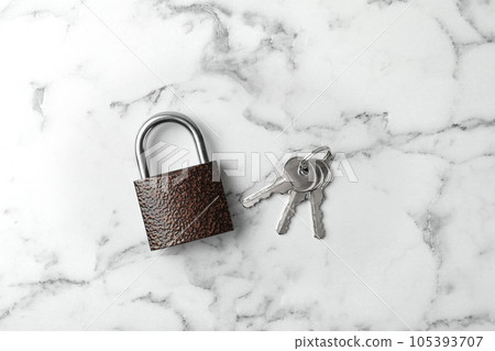 Steel padlock and keys on white marble background, top view. Safety concept Steel padlock and keys on white marble background, top view. Safety concept 105393707