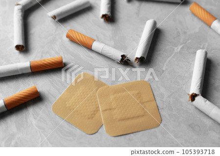 Nicotine patches and broken cigarettes on grey table Nicotine patches and broken cigarettes on grey table 105393718