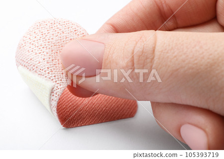 Woman putting sticking plaster on white background, closeup. First aid item 105393719