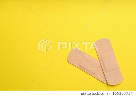 Sticking plasters on yellow background, top view. Space for text 105393734