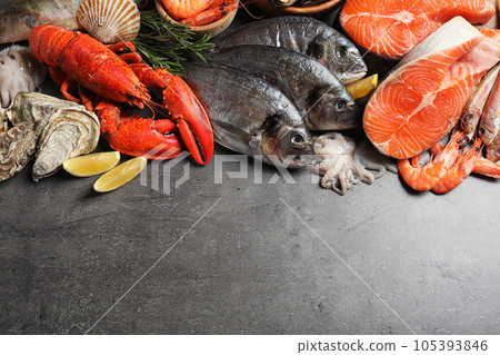 Fresh fish and different seafood on grey table, flat lay. Space for text Fresh fish and different seafood on grey table, flat lay. Space for text 105393846
