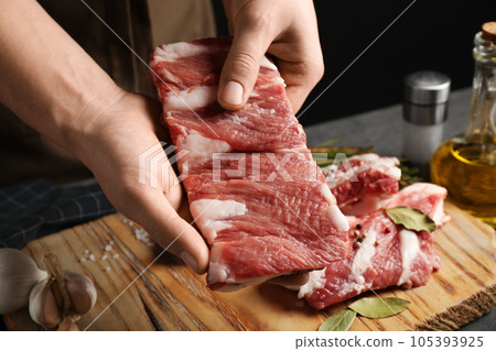 Man holding raw ribs at table, closeup Man holding raw ribs at table, closeup 105393925