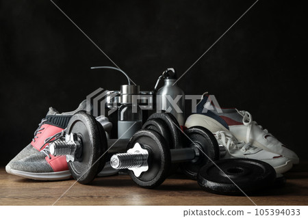 Gym equipment and accessories on wooden floor against dark background Gym equipment and accessories on wooden floor against dark background 105394033