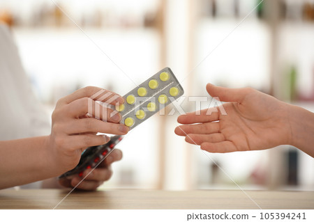 Pharmacist giving medicine to customer in drugstore, closeup 105394241