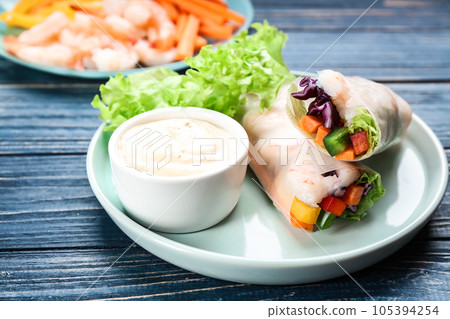 Delicious rolls wrapped in rice paper served on blue wooden table 105394254