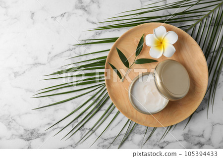 Composition with cosmetic product and tropical flower on white marble table, top view. Space for text 105394433