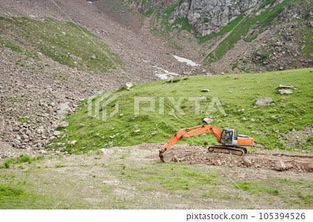Excavator works in the highlands. Clears the consequences of a mudslide in the gorge of the mountains. repair and expansion of a road 105394526