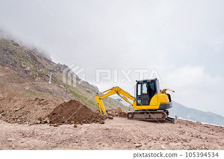 Excavator works in the highlands. Makes a trench for communications. water and electricity. in the gorge of the mountains. repair and expansion of a road 105394534