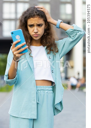 Surprised preteen child kid use smartphone loses bad news fortune loss, fail outdoors in city street 105394575