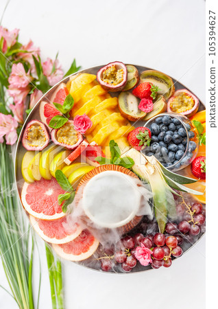 Raw fruits berries assortment platter on the plate, on the white table 105394627