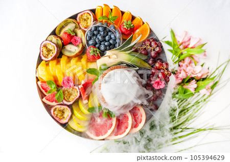 Raw fruits berries assortment platter on the plate, on the white table Raw fruits berries assortment platter on the plate, on the white table 105394629