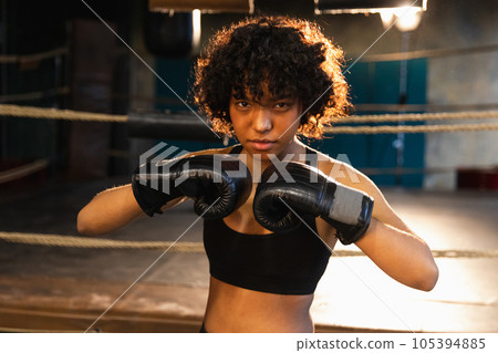 Outcry independent girl power. Angry african american woman fighter with boxing gloves looking serious aggressive standing on boxing ring. Strong powerful fighter girl training punches Outcry independent girl power. Angry african american woman fighter with boxing gloves looking serious aggressive standing on boxing ring. Strong powerful fighter girl training punches 105394885