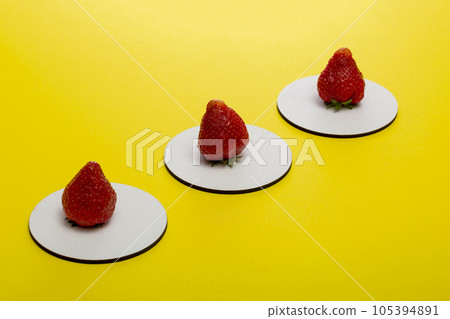 Three ripe strawberries on white stands on a yellow background Three ripe strawberries on white stands on a yellow background 105394891