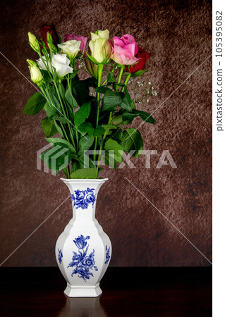 Fresh Flowers in a Ceramic Flower Vase on a Polished Wooden Table Top 105395082