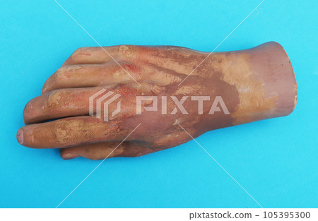 Wrist of man's plastic hand on blue background. 105395300