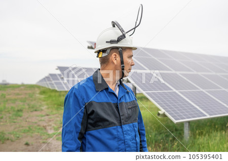 Service Engineer man standing with arms crossed in front of solar panels. Technician maintenance solar cells on Solar Energy Plant under morning sunlight. Technology solar energy renewable Service Engineer man standing with arms crossed in front of solar panels. Technician maintenance solar cells on Solar Energy Plant under morning sunlight. Technology solar energy renewable 105395401