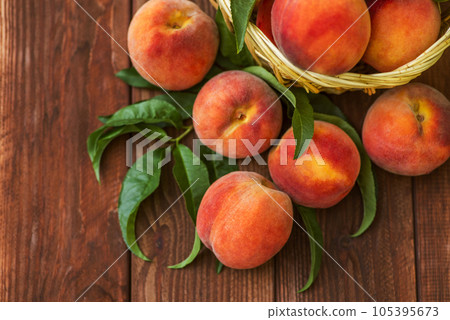 Freshly picked peaches in basket on a brown wooden background Freshly picked peaches in basket on a brown wooden background 105395673