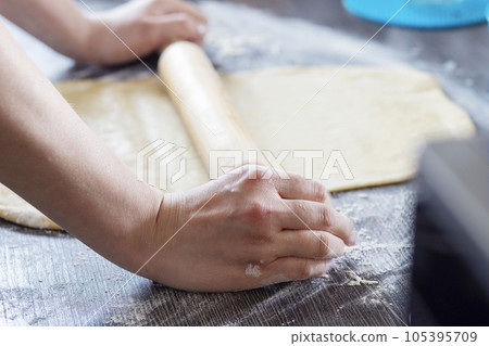 Hands, rolling-pin and dough for bread, pasta or pizza on wooden table. 105395709