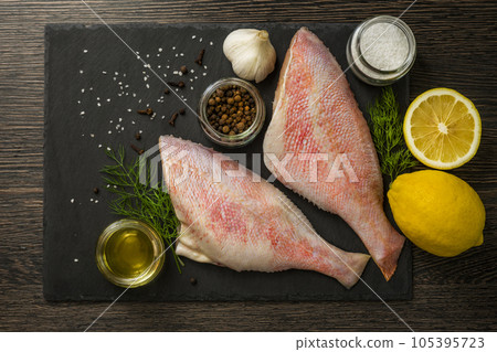 Sea perch on black board. Sea bass on black board with ingredients for cooking 105395723