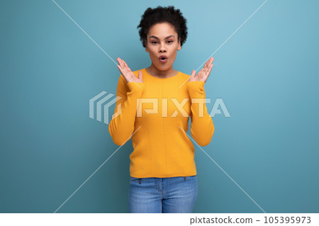 surprised joyful young brunette latin female adult in yellow sweater is happy 105395973