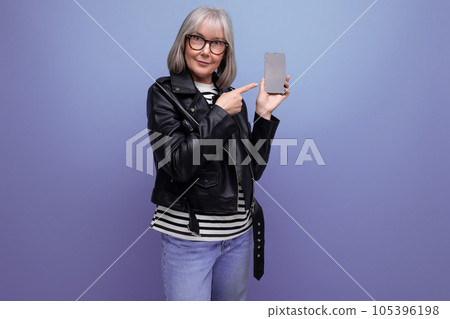 60s modern old woman blogger with gray hair uses the Internet from a smartphone on a bright 105396198