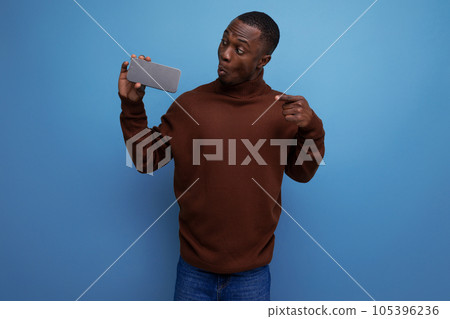 portrait of a surprised young african man with a smartphone in his hands isolated background with portrait of a surprised young african man with a smartphone in his hands isolated background with 105396236