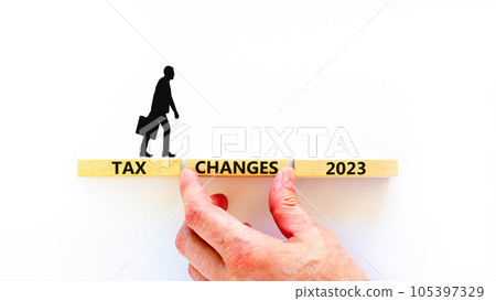 Tax changes 2023 symbol. Concept words Tax changes 2023 on wooden blocks on a beautiful white table white background. Businessman icon. Businessman hand. Business Tax changes 2023 concept. Copy space. 105397329