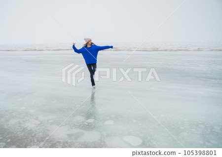 Caucasian woman in a blue sweater skating on a frozen lake. Caucasian woman in a blue sweater skating on a frozen lake. 105398801