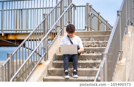 A man sitting on the stone steps and using a computer 105400373