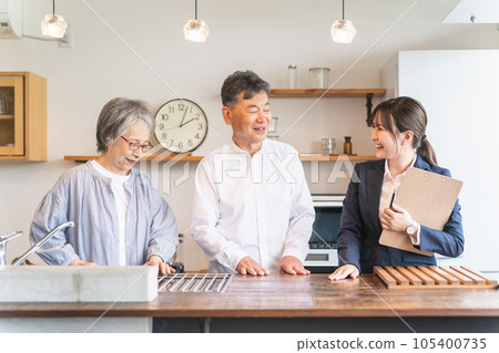 Business woman explaining to an elderly couple at a housing exhibition hall, model room, house maker (kitchen, top plate) 105400735