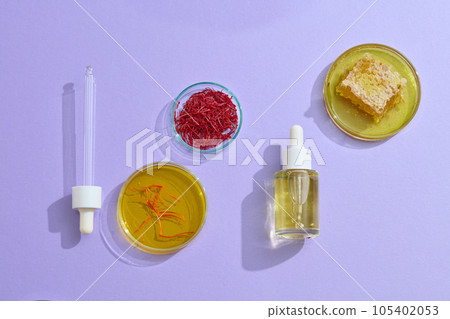 Scene for cosmetic serum advertisement with expensive ingredients like saffron and honey on purple background. Saffron, a spice that originated in Asia - a healing and health-boosting plant 105402053