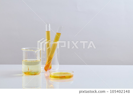 Yellow liquid with saffron contained inside test tubes, petri dishes and beaker. Vacant space in the right side for organic product advertising of Saffron extract Yellow liquid with saffron contained inside test tubes, petri dishes and beaker. Vacant space in the right side for organic product advertising of Saffron extract 105402148