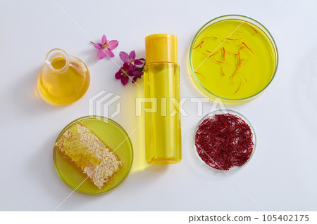 Plastic bottle decorated with honeycomb, saffron and a conical flask filled with yellow liquid. Modern research also supports the claimed benefits of saffron Plastic bottle decorated with honeycomb, saffron and a conical flask filled with yellow liquid. Modern research also supports the claimed benefits of saffron 105402175