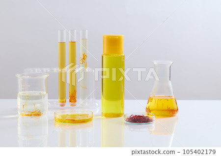 Unbranded bottle filled with liquid and arranged with laboratory glassware over white background. Saffron is the most expensive spice in the world 105402179