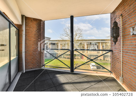 an open balcony with brick walls and black iron railings, looking out onto the garden from the front door 105402728