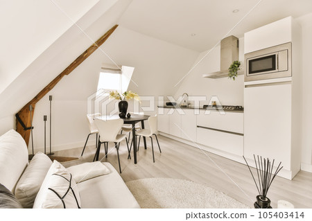 a living room and kitchen area in a loft apartment with white walls, hardwood flooring and light wood floors 105403414