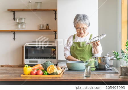 Asian elderly woman cooking using IH cooking heater in home kitchen Asian elderly woman cooking using IH cooking heater in home kitchen 105403993