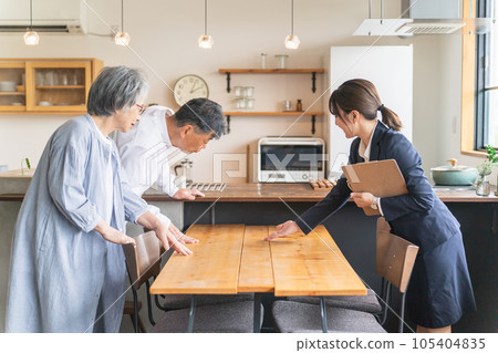 A business woman and an elderly couple explaining the materials of the housing exhibition hall, model room, and house maker table 105404835
