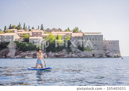 Young women Having Fun Stand Up Paddling in blue water sea near st stefan island in Montenegro. SUP 105405031