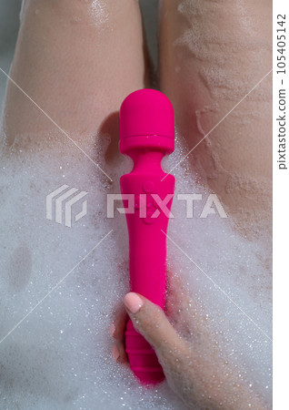 Woman lies in a bubble bath and uses a vibrator. Woman lies in a bubble bath and uses a vibrator. 105405142