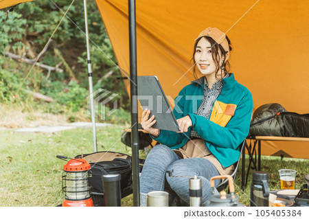 A young female camper camping solo at a campsite (reading/reading a book) A young female camper camping solo at a campsite (reading/reading a book) 105405384